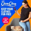 A lifestyle shot of a woman holding the portable lint roller standing next to a chair where a cat is resting