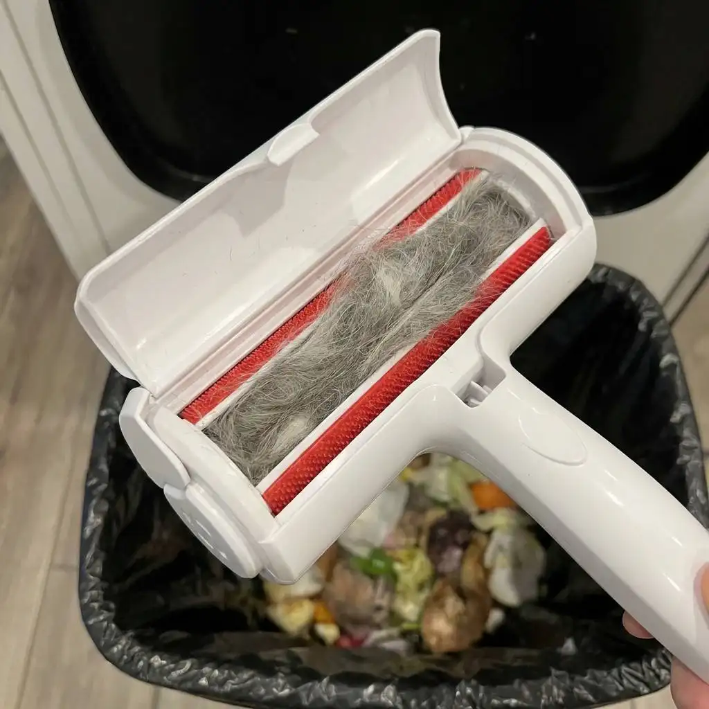 Open kitchen trash can storage chamber filled with a dense bundle of grey and white pet fur.